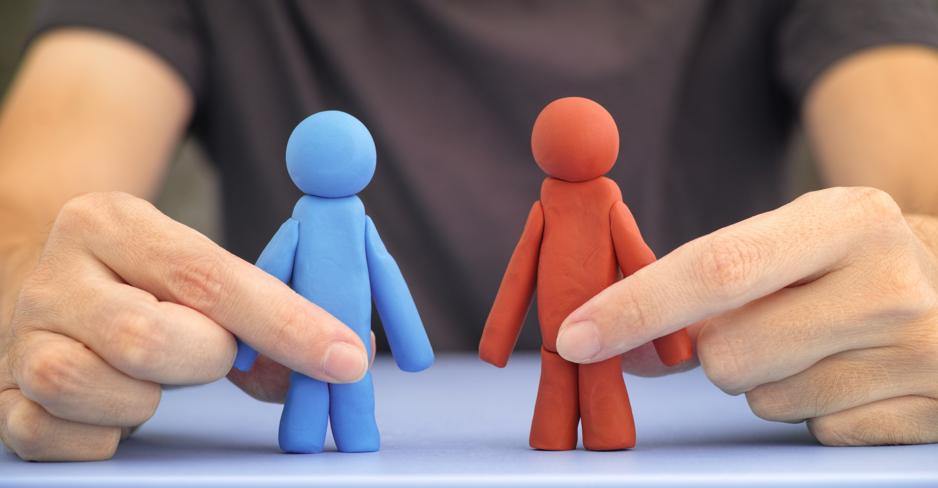 Man holding blue and red figures in his hands