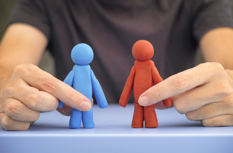 Man holding blue and red figures in his hands